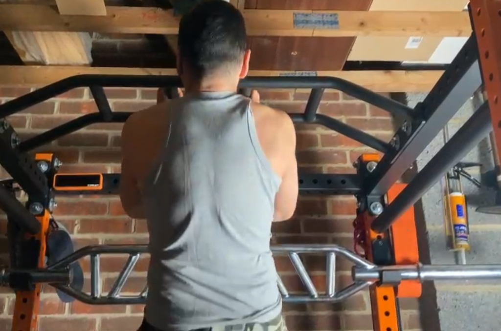 a man does a pullup in a squat rack