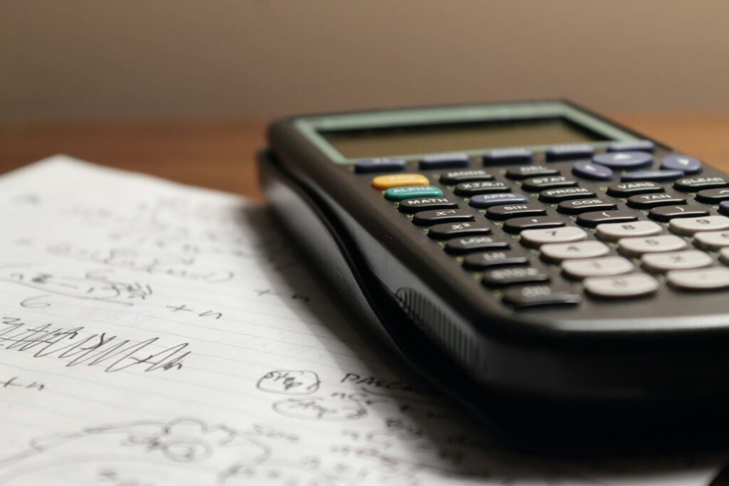 A calculator on a sheet of paper covered with mathematical calculations.