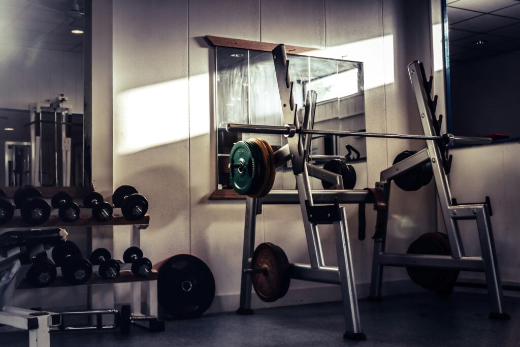 Gym equipment, including a barbell, a rack, and dumbbells.